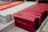 A collection of rectangular soap bars arranged neatly on a tray. The soaps are primarily in shades of red, with the word 'CERISE' clearly visible embossed on the surface of the foremost bar. Also visible in the background are soap bars of other colors, including white and orange.