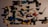 A collection of colorful plastic toy parts scattered on a surface. The parts include various shapes and sizes, such as connectors, rods, and small figures, predominantly made from interlocking pieces. The colors range from black, blue, green, yellow, white, red, to purple, with shadows cast by the parts adding to the scattered arrangement.