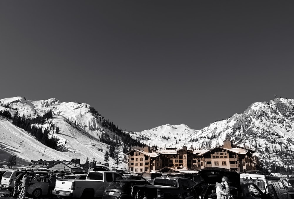 a group of cars parked in a parking lot in front of a mountain