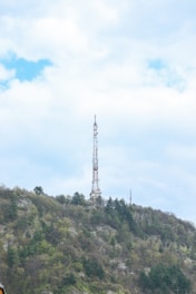 A radio antenna tower transmitting signals over a green landscape.