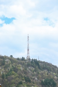 A radio antenna tower transmitting signals over a green landscape.