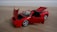 A red toy convertible car is placed on a wooden surface. The car's doors, trunk, and hood are open, revealing the interior details and engine space. The wheels are silver and shiny, and the overall condition of the toy is new.