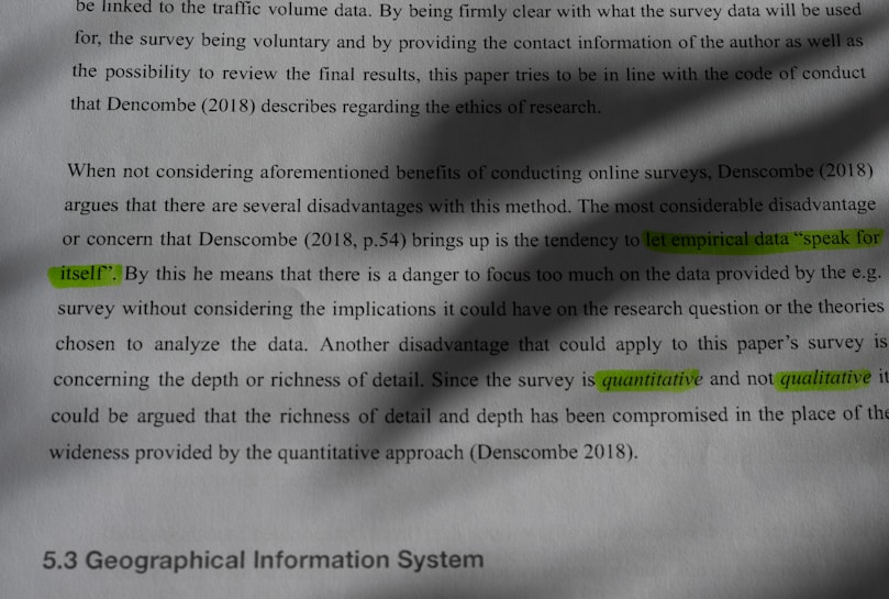 A section of printed text discusses the disadvantages of online surveys, referencing Denscombe (2018). Specific phrases are highlighted in green, such as 'speak for itself,' 'let empirical data,' 'quantitative,' and 'qualitative.' The text mentions concerns about focusing on empirical data without considering its implications and compares quantitative methods to qualitative ones. Shadows partially obscure the text, and the section is titled '5.3 Geographical Information System.'