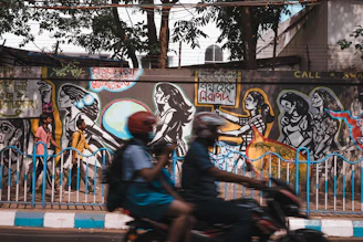 A vibrant mural featuring black artists at work blending past and present styles, set against a Detroit cityscape.