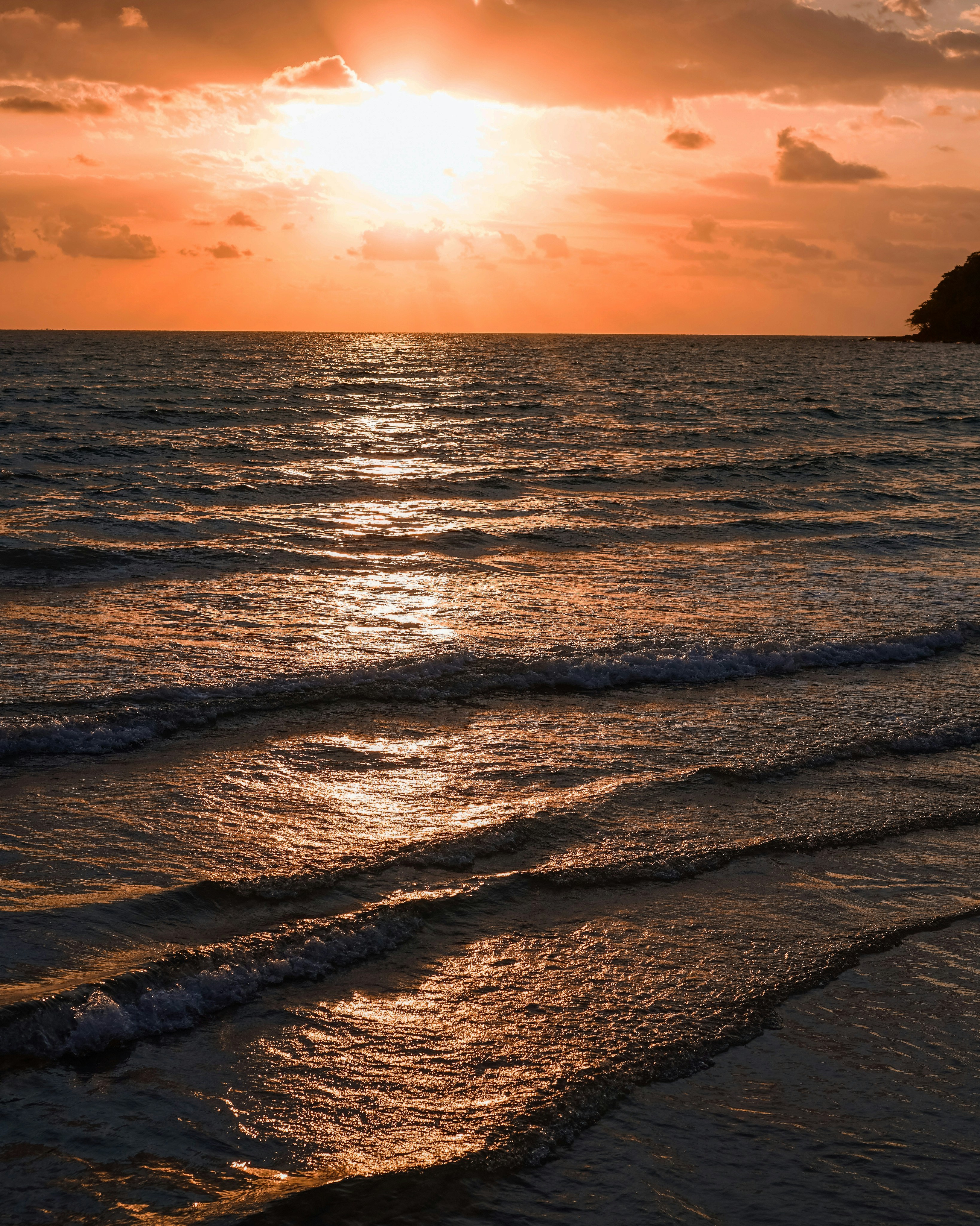 a beach with waves and a sunset