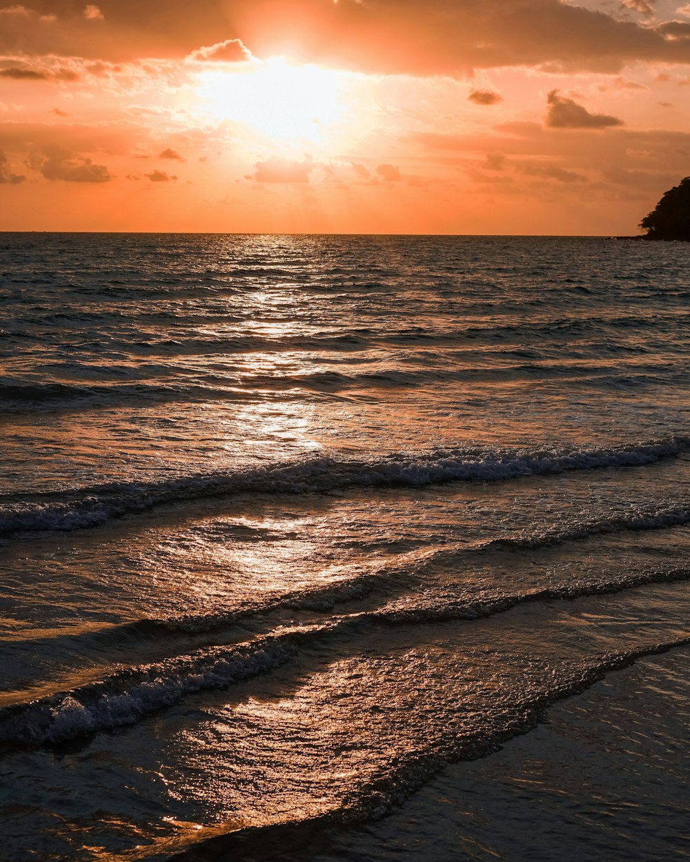 a beach with waves and a sunset