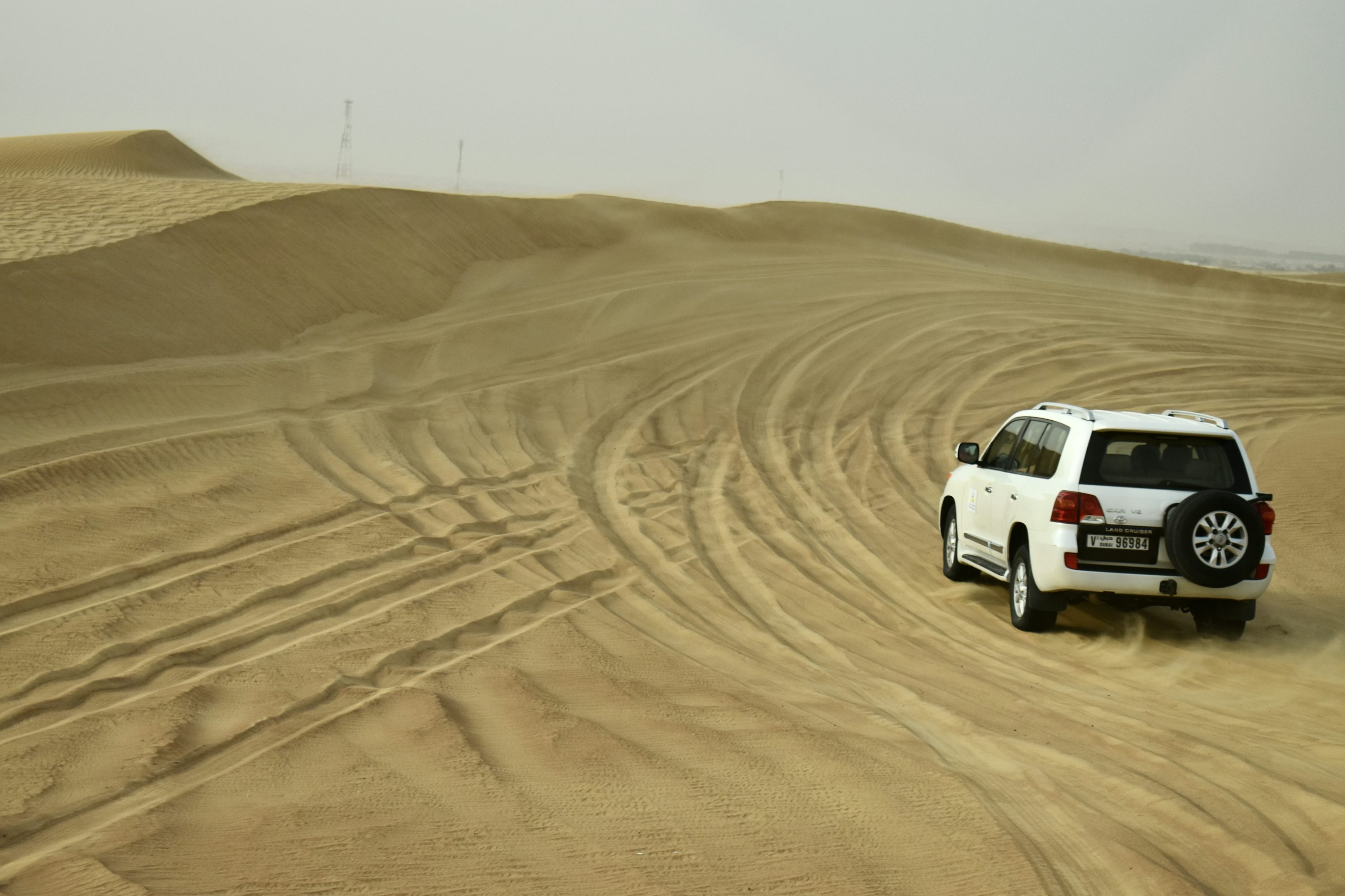 a white car driving through a desert