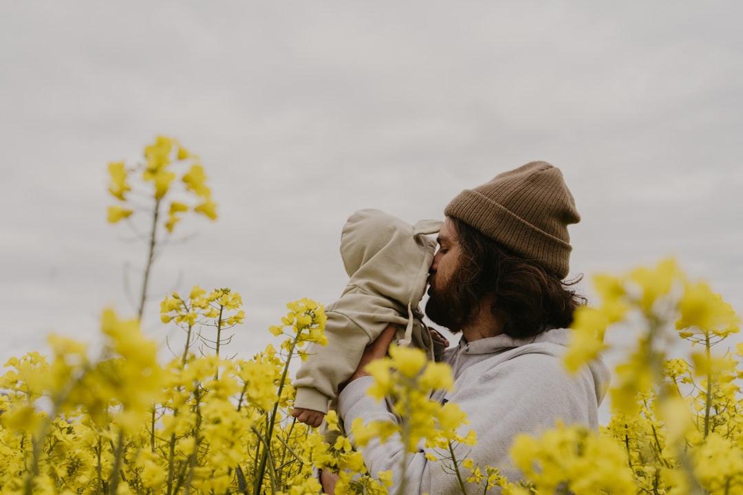 a man and woman kissing in a field of yellow flowers,
