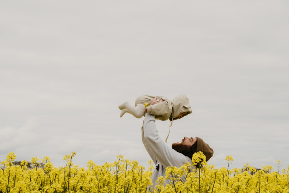 a person holding a baby in a field of yellow flowers