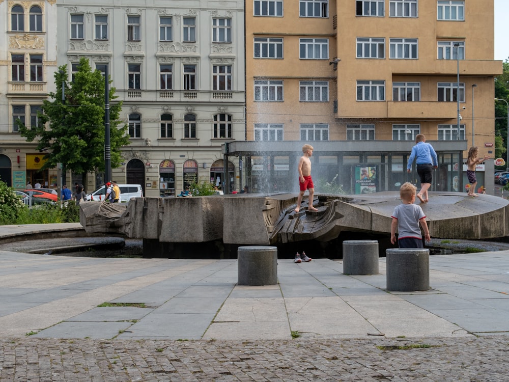 a group of people playing in a fountain in a city