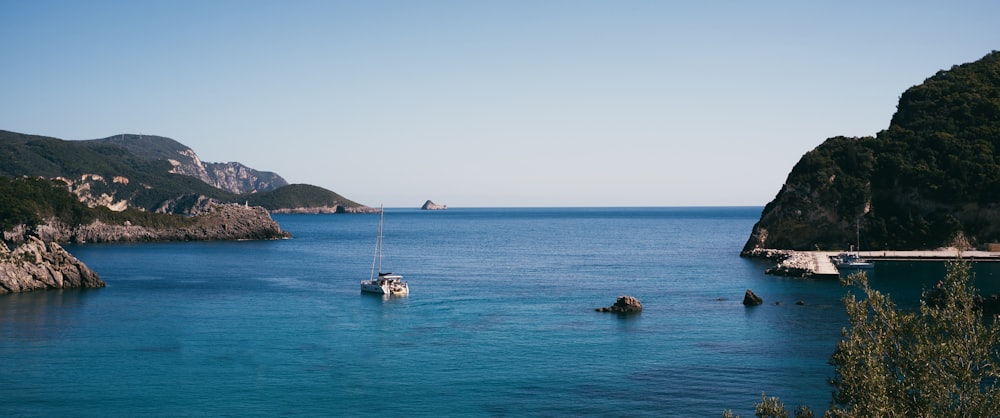 a body of water with boats in it and hills in the back