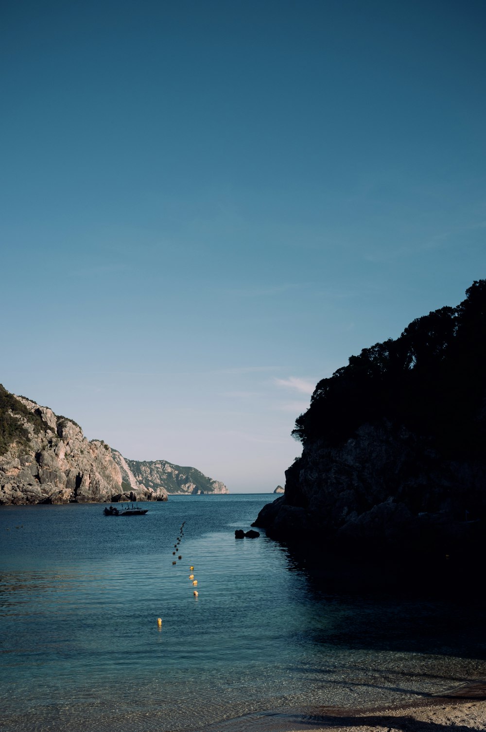 a body of water with boats in it and a rocky cliff in the background