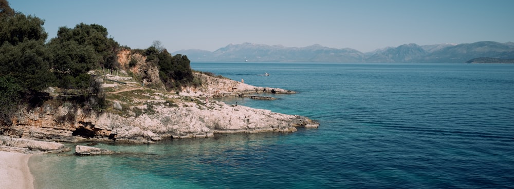 a rocky beach with trees and hills