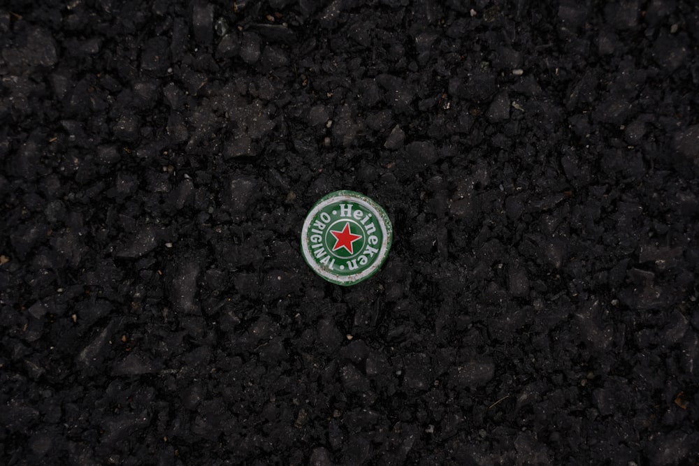 a green and white circular object on a rocky surface