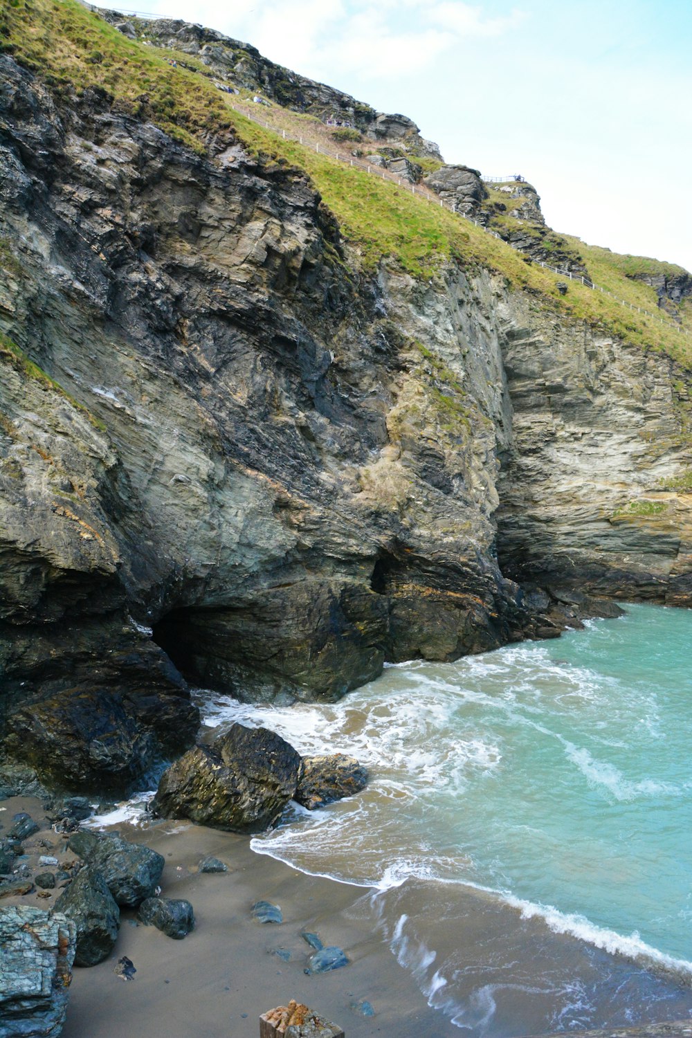 a rocky cliff next to a beach