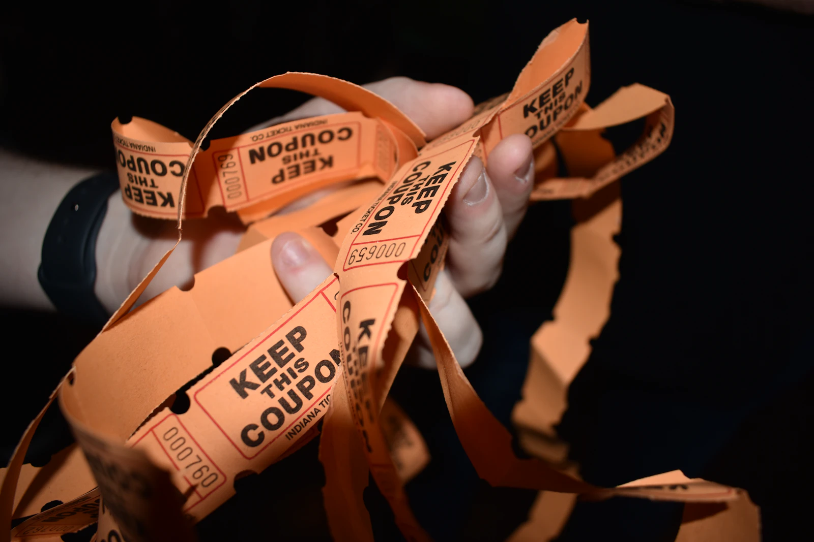 A hand holding a fistful of orange raffle tickets