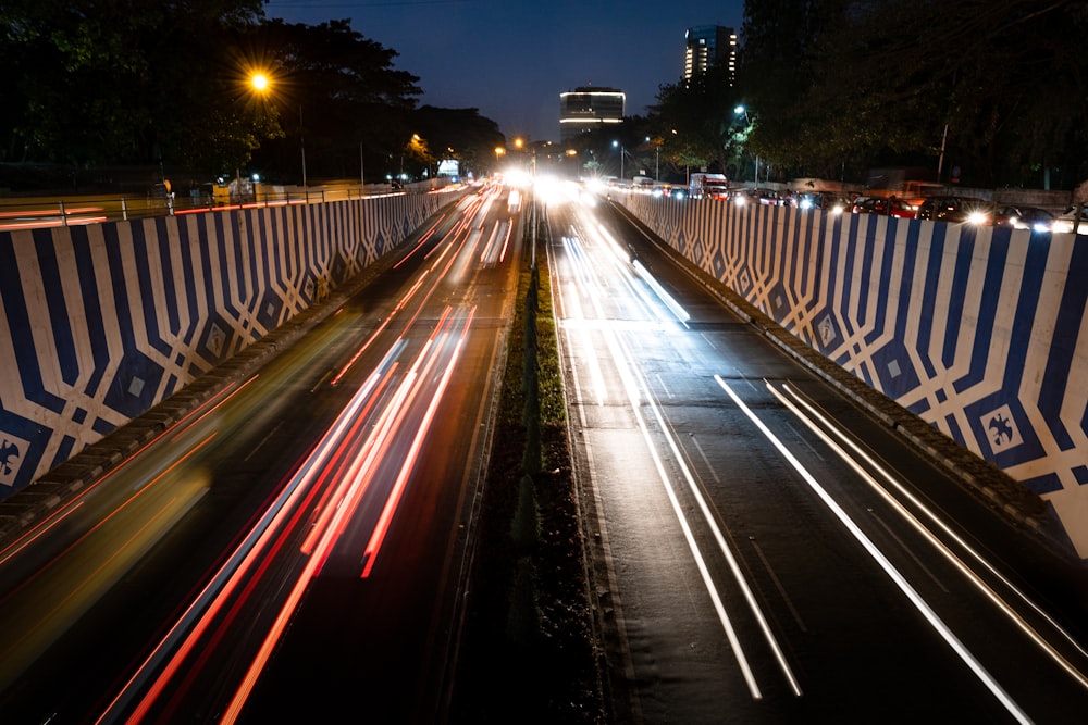 a highway with a blue and white wall and a road with cars on it