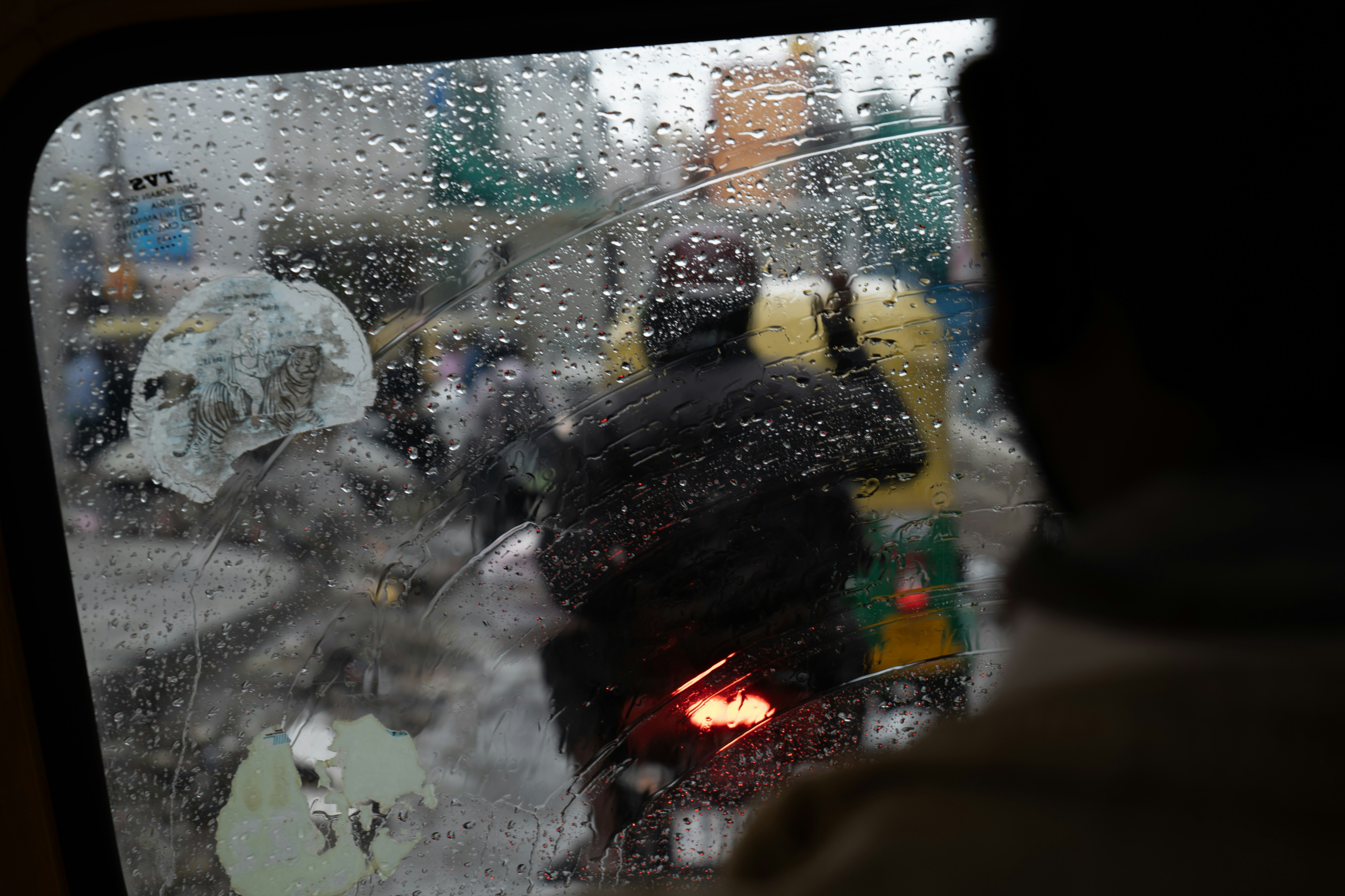 People with umbrellas seen through a wet window