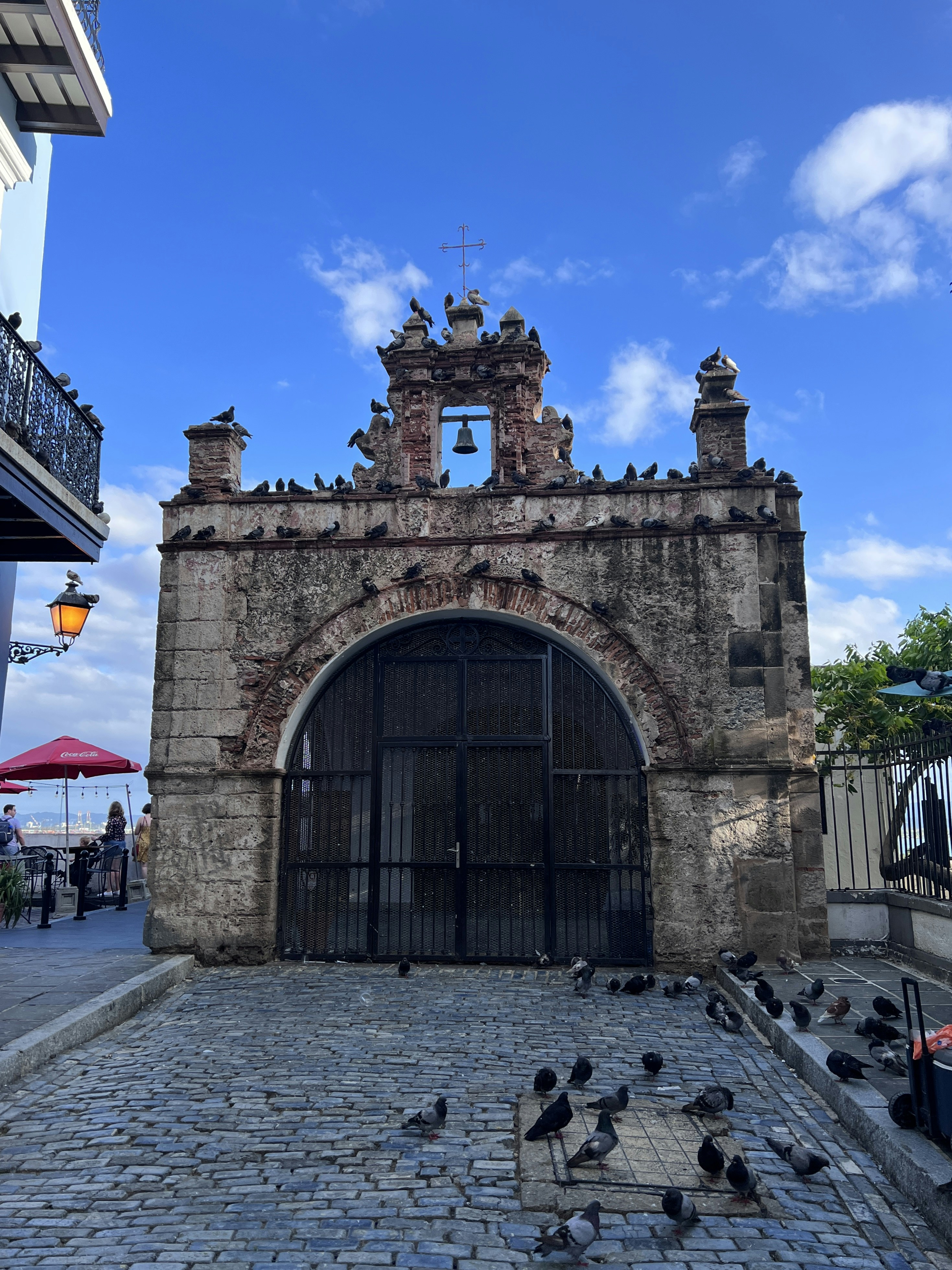 a stone building with a gate and a group of pigeons