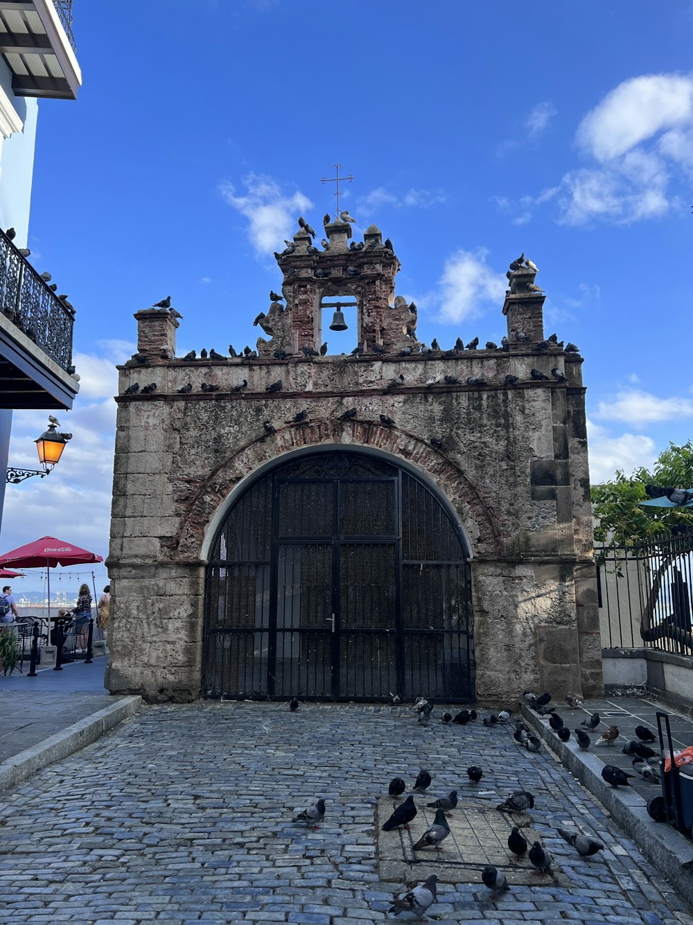 a stone building with a gate and a group of pigeons