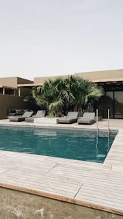 A cozy poolside seating area with modern furniture and subtle earth-toned accents blending with the landscape