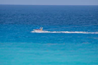 A white motorboat cruising on crystal-clear blue waters.