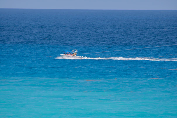 A bright WorldCat 325DC boat cutting through crystal-clear light blue water under a sunny sky