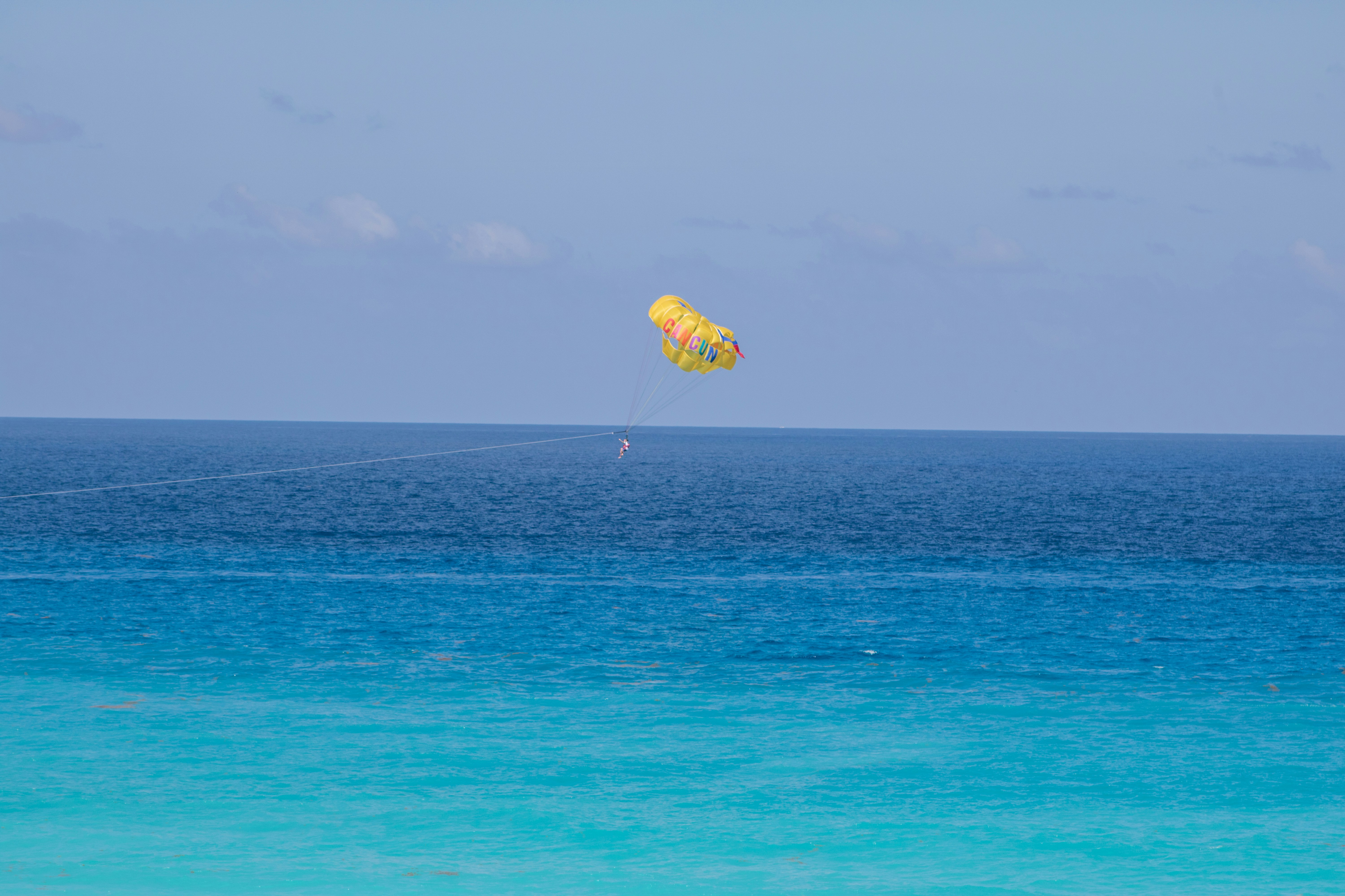 a person in the air with a parachute over a body of water
