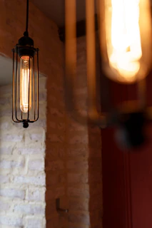 A dramatic shot of an industrial pendant light with aged steel and glowing filament bulbs.