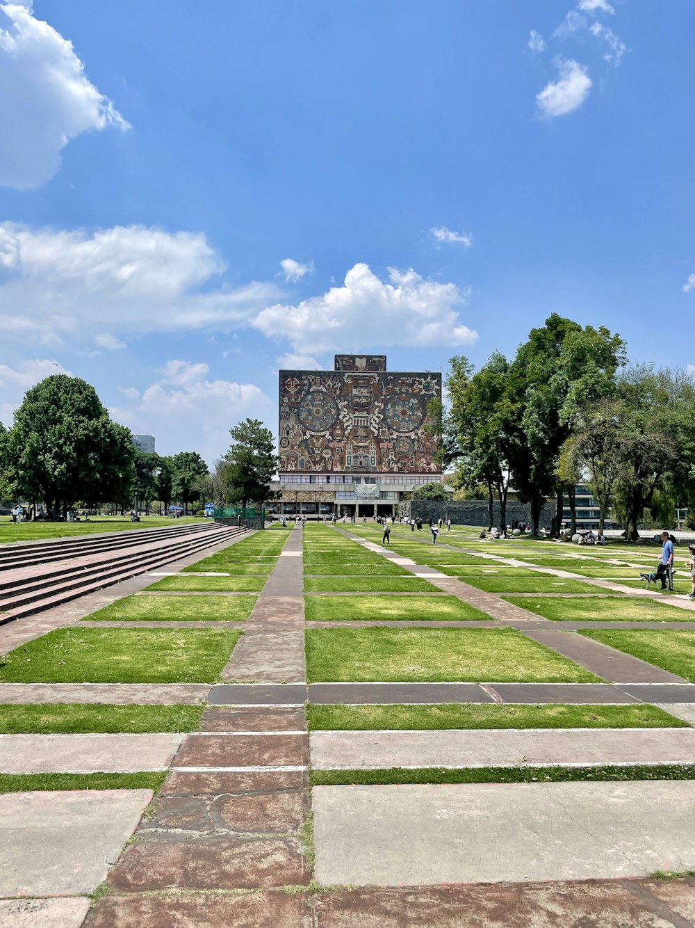 a large brick structure with a grass field and trees in front of it