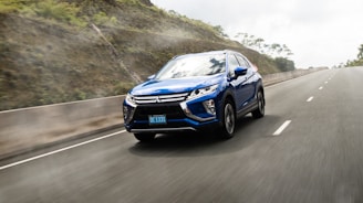 Dynamic shot of a Hyundai SUV driving through lush green hills under a bright blue sky.