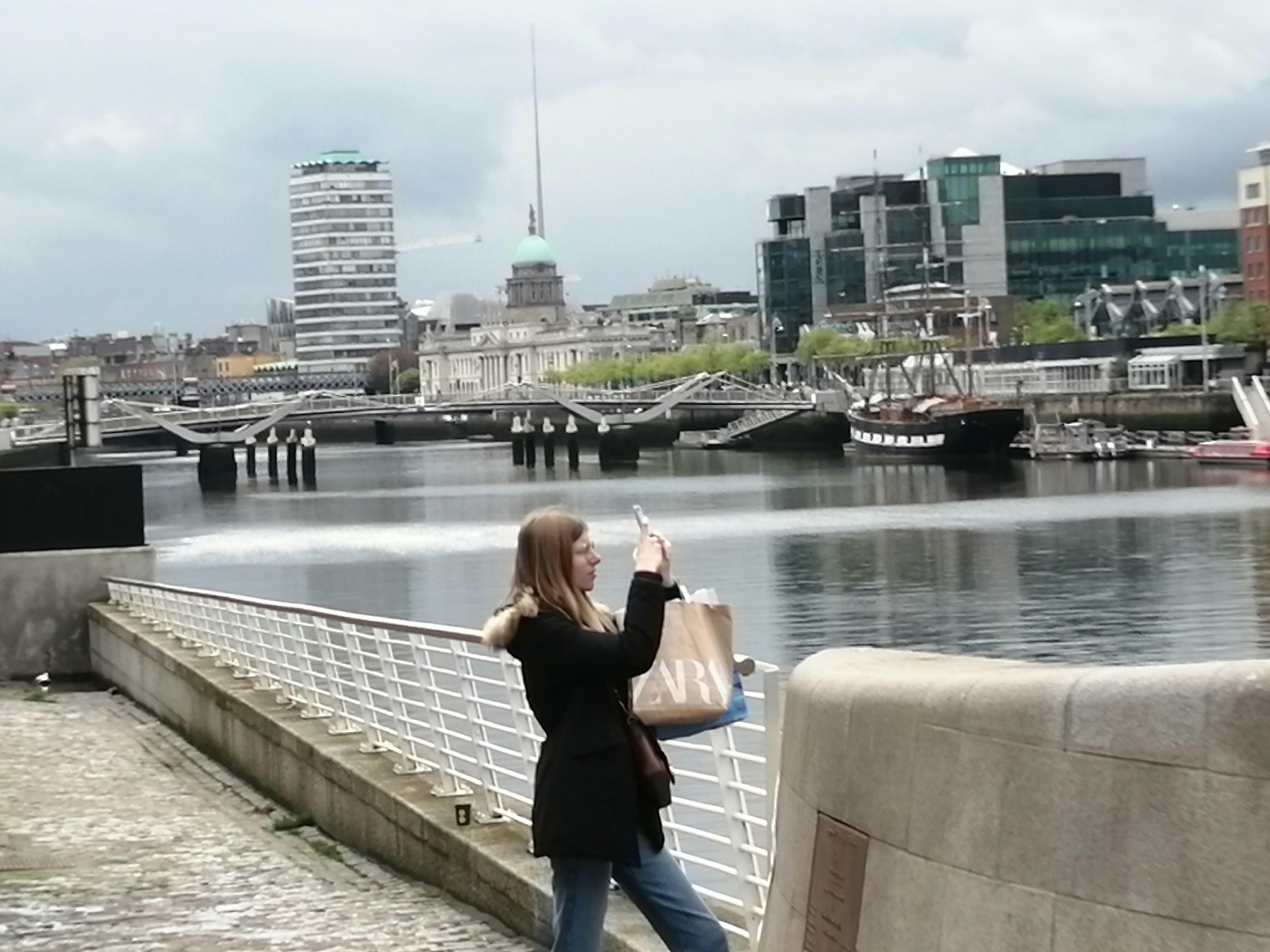 a person taking a picture of a body of water with a city in the background