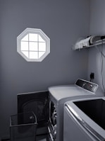 High-efficiency washing machine with clear glass door in a laundry room.