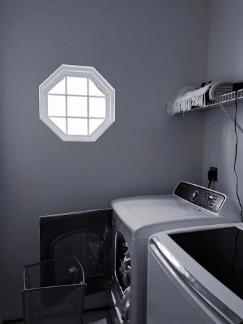 A bright laundry room featuring a sleek, front-loading smart washer and dryer set with intuitive controls.