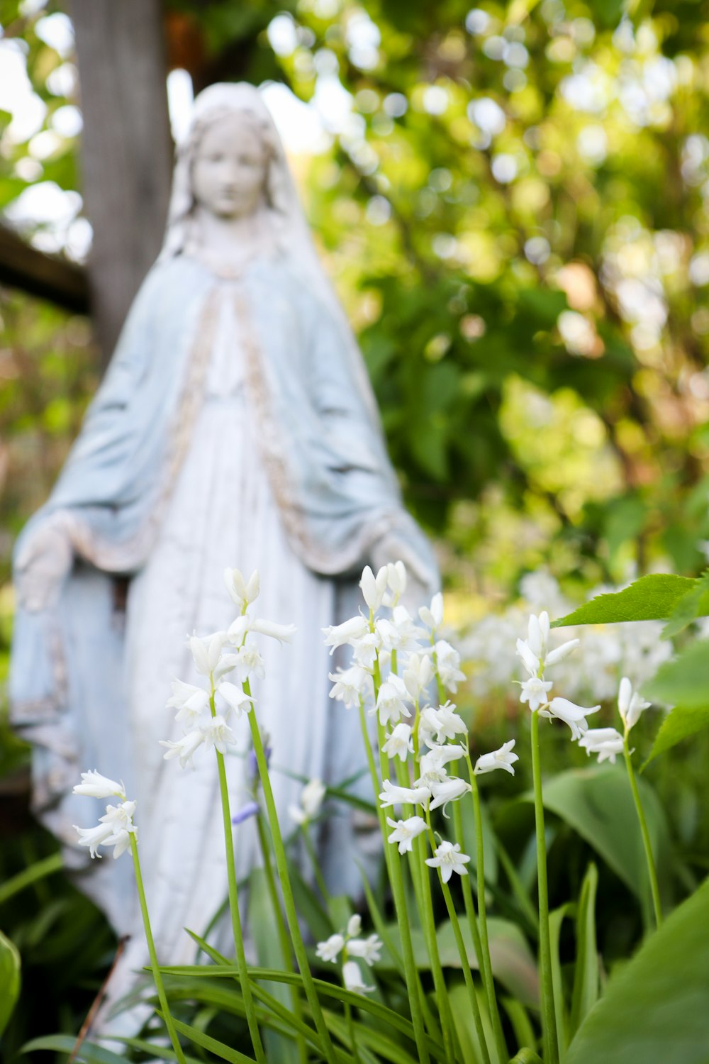 a statue of a person in a white dress surrounded by white flowers