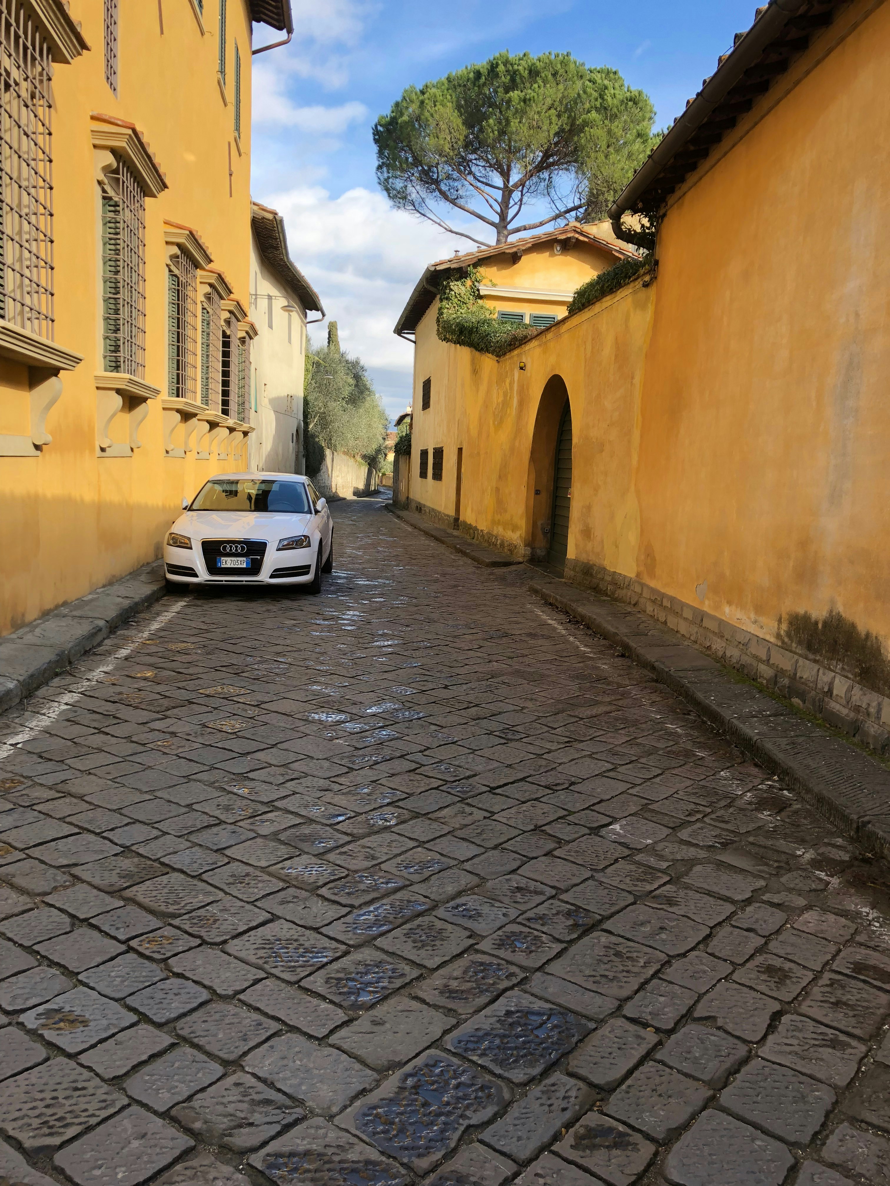 a car parked on a cobblestone street between buildings
