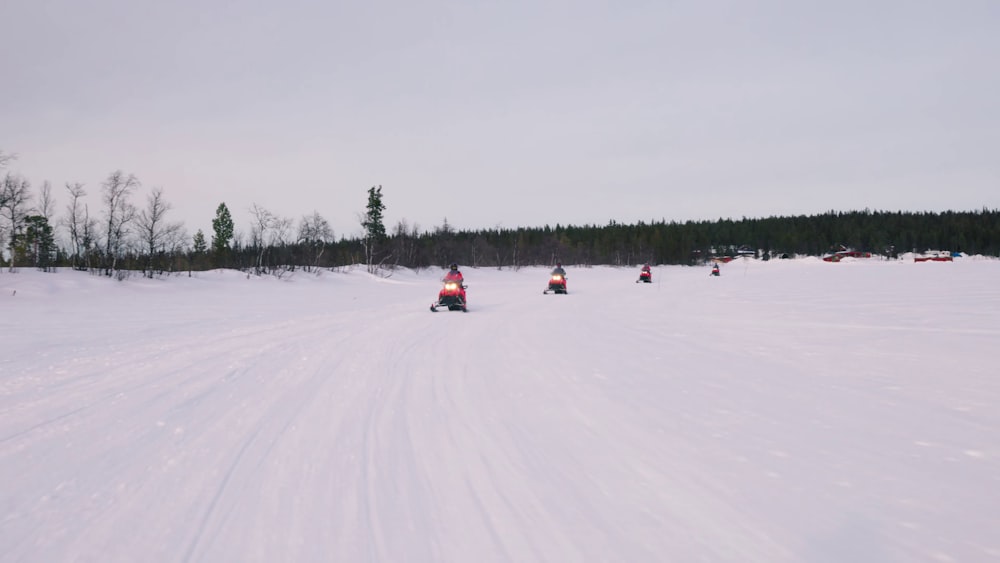 a group of people riding snowmobiles on a snowy field