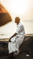 A serene image of Dr. Abraham Muthunayagam sitting by the Travancore coast, reflecting on his life's work.