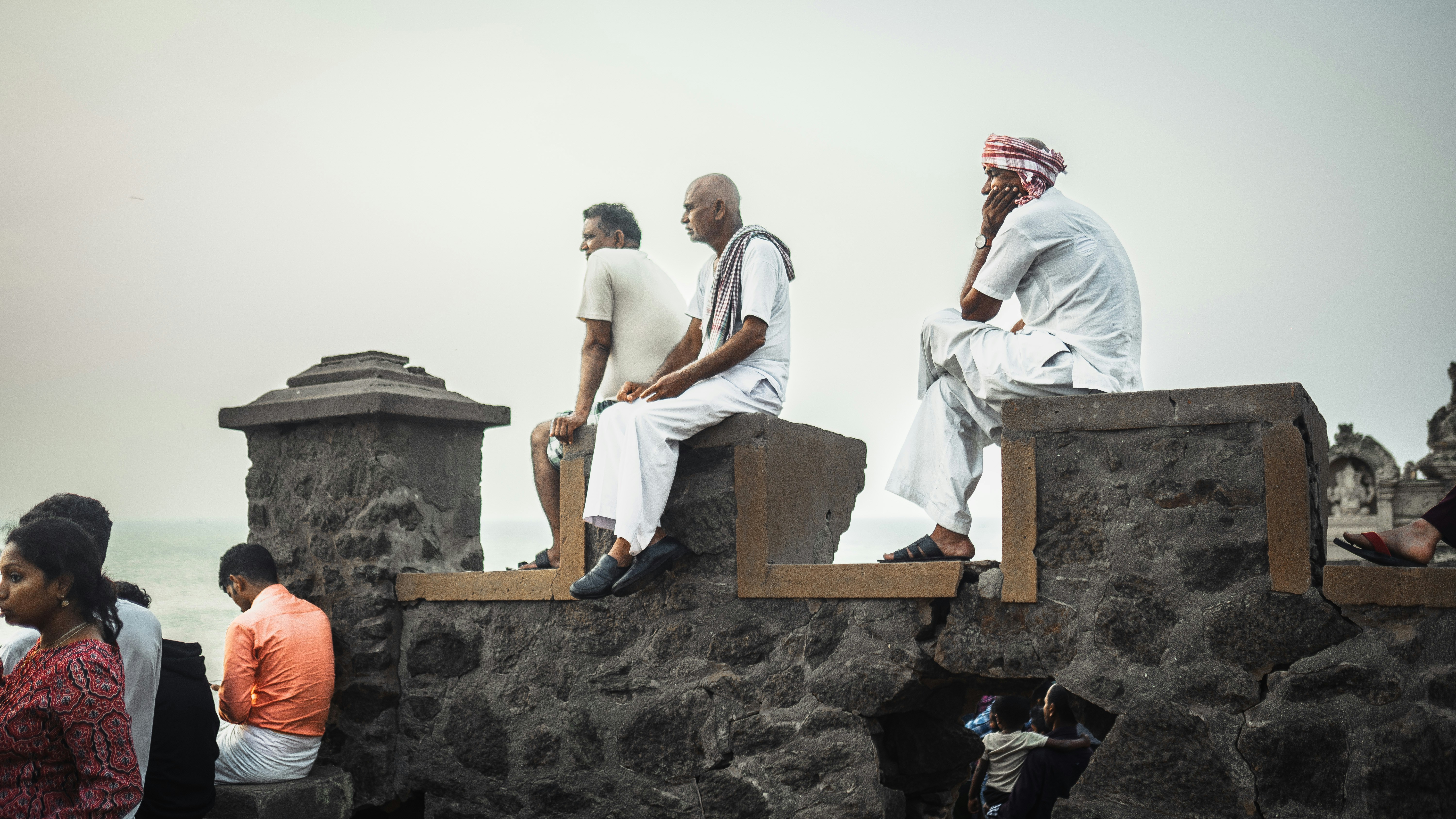 a group of people sitting on a stone wall