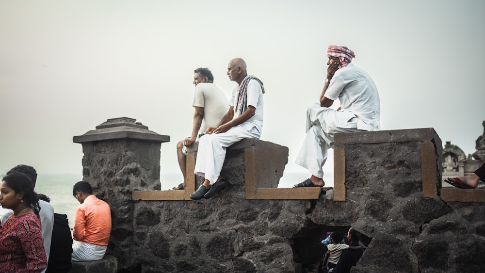 a group of people sitting on a stone wall