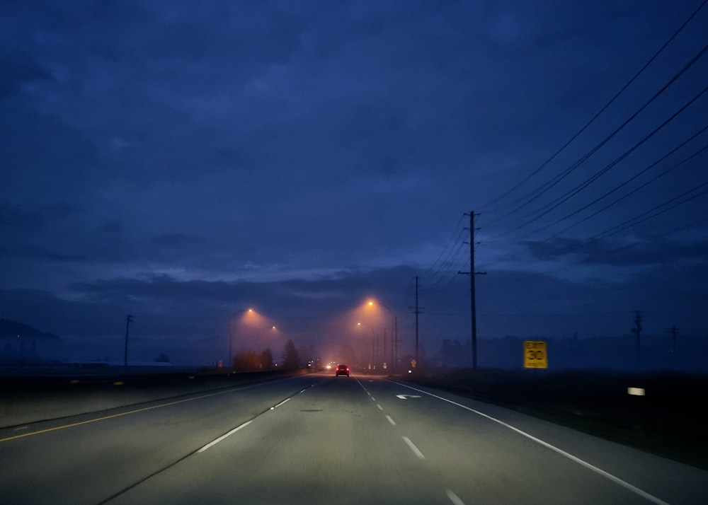 a road with cars on it and a sunset in the background