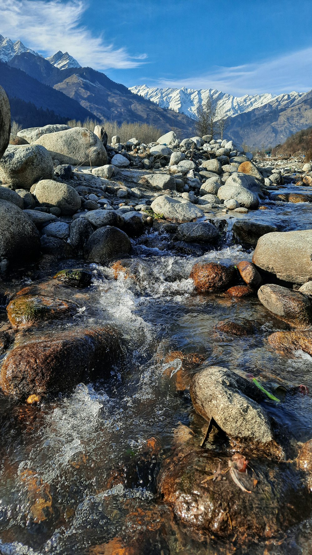 a river with rocks and mountains in the background