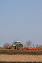 A tractor moving through the apple orchard under a clear blue sky.