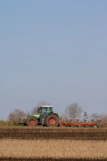 A tractor moving through the apple orchard under a clear blue sky.
