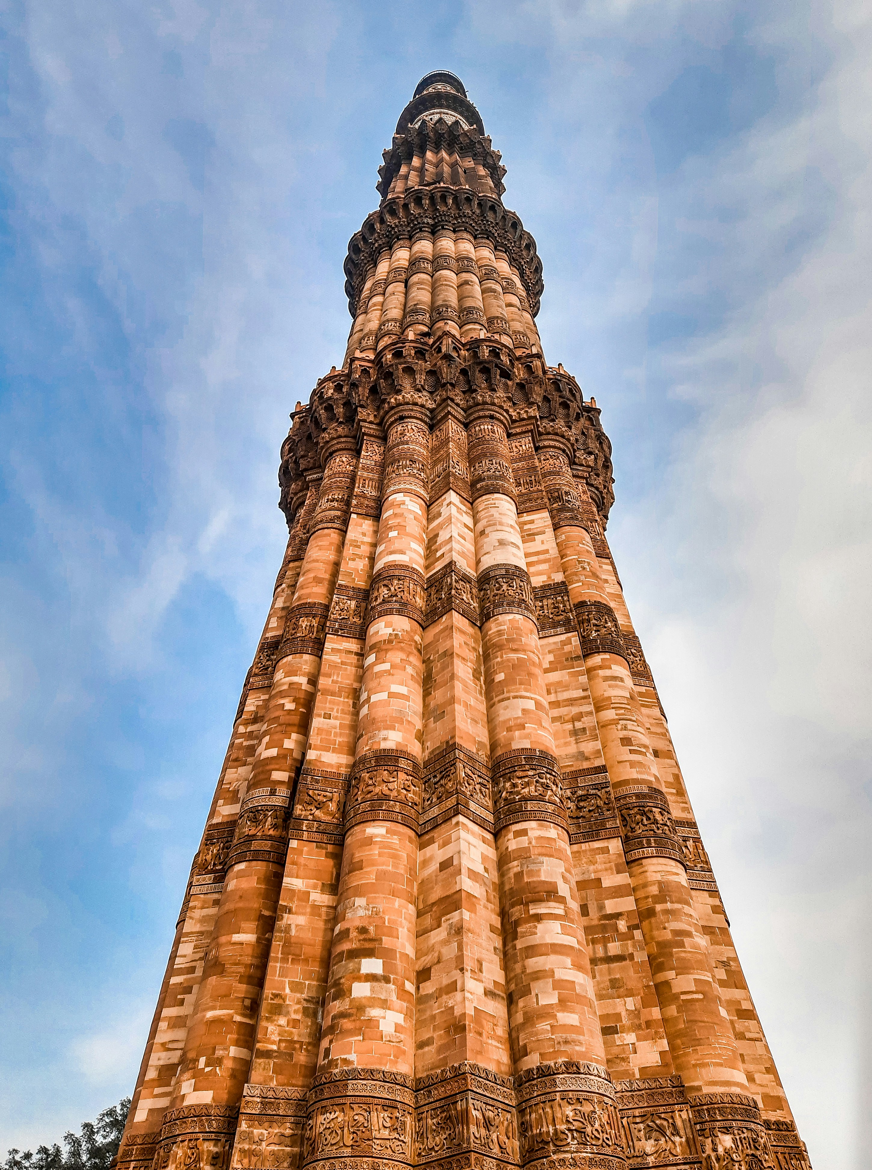 una torre alta con un cielo azul con Qutub Minar al fondo