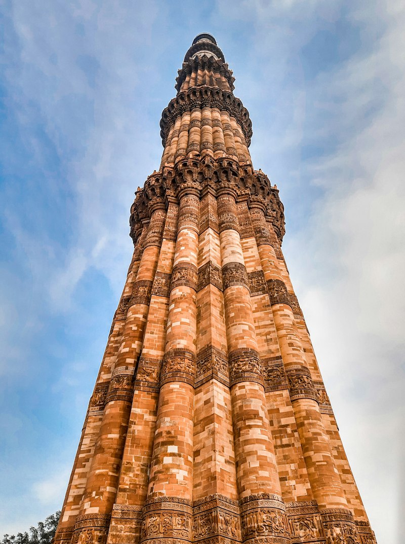 View of the Qutub Minar tower complex in Delhi under a clear sky