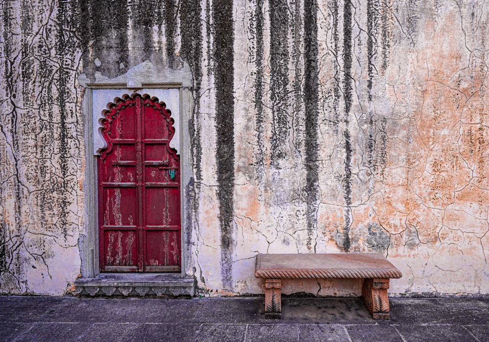 a bench sits in front of a red door