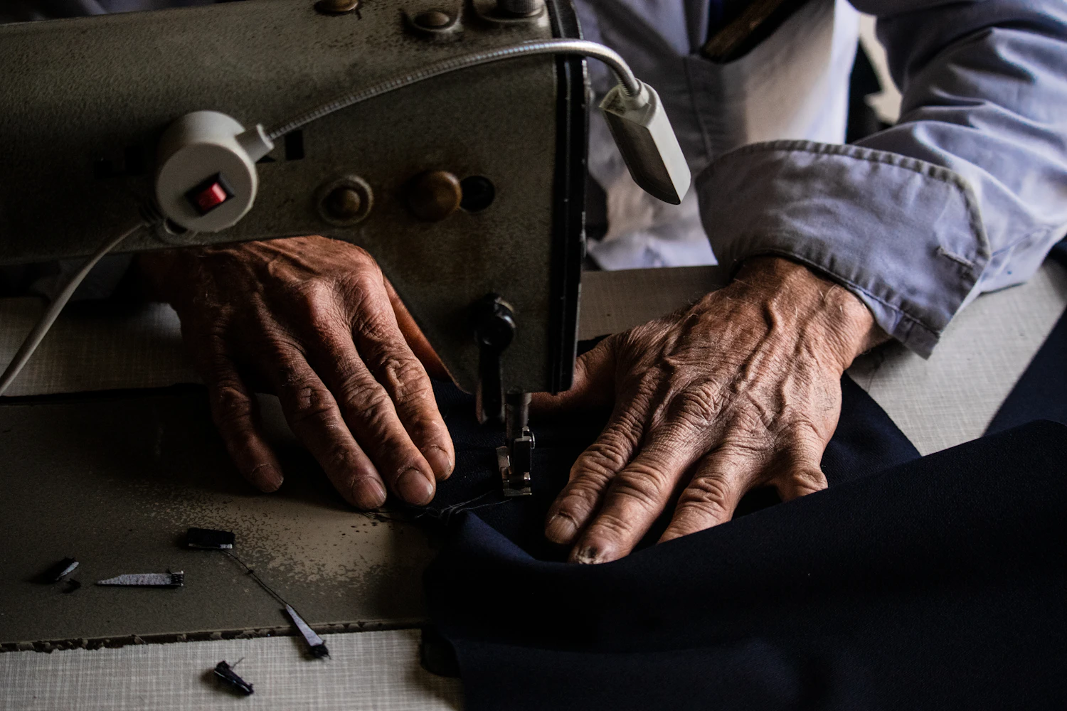 Two hands guiding cloth under the foot of a machine