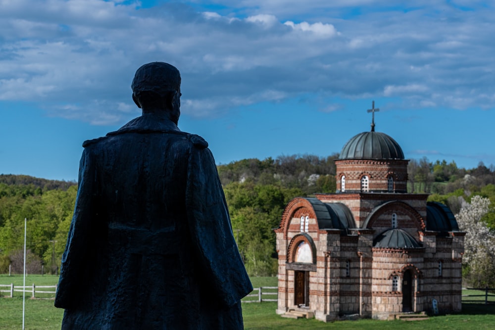 a statue of a person in front of a building with a cross on top