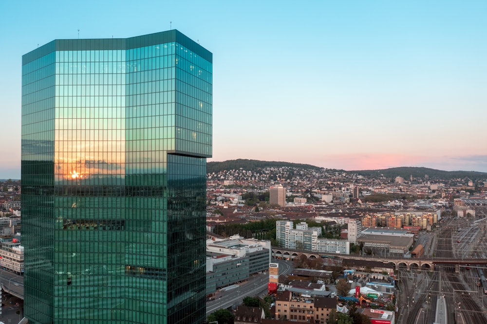 a tall glass building with a city below